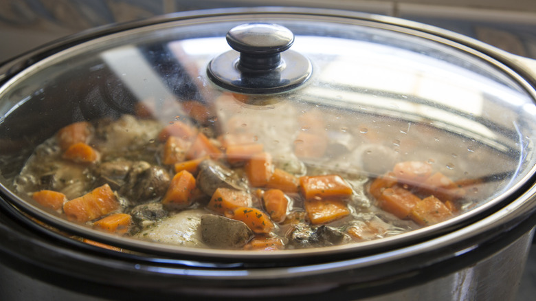 Carrots, mushrooms and meat visible through lid of a slow cooker
