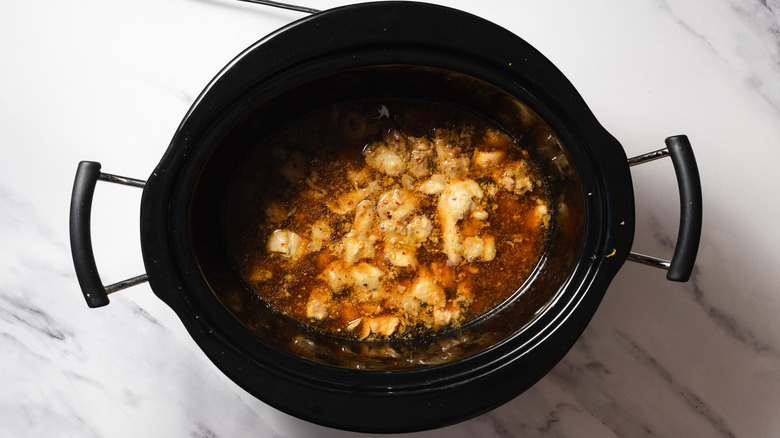 Cooked orange chicken in sauce in slow cooker