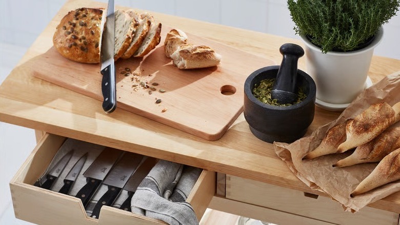 Ikea wooden portable island with cutting board, bread, and mortar and pestle on top