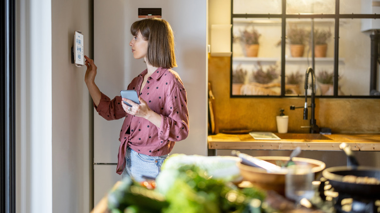 A woman using a tablet on the wall in the ktichen