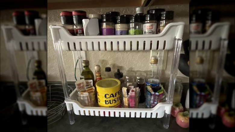 A two-tiered rack on a kitchen counter holds spices and coffee.