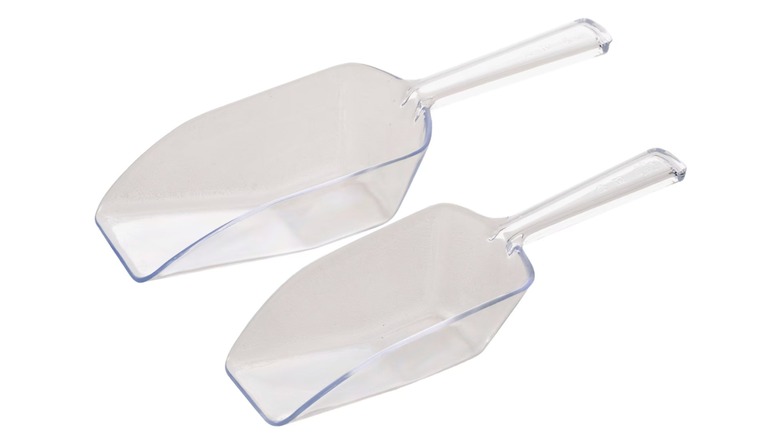Two clear plastic scoops against a white background
