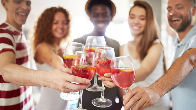 friends toasting with raspberries in drink