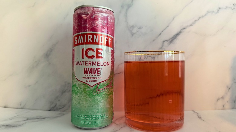 Can of Watermelon Wave Smirnoff Ice next to glass of Smirnoff Ice on marble surface