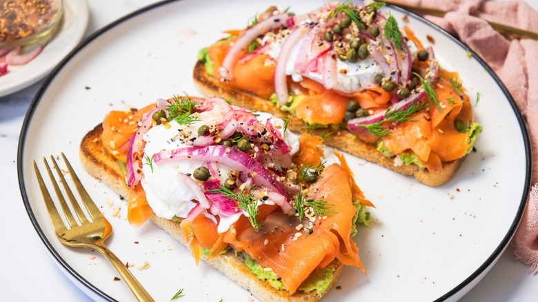 Two slices of smoked salmon breakfast toast on white plate.