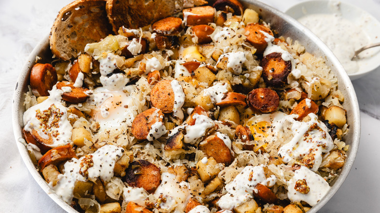 Skillet with potatoes, sausage, eggs, and mustard remoulade sauce on the side