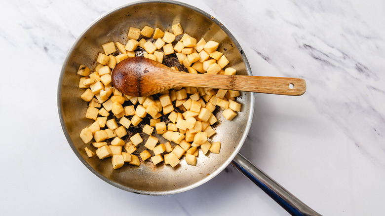Hashbrowns and wooden spoon in skillet
