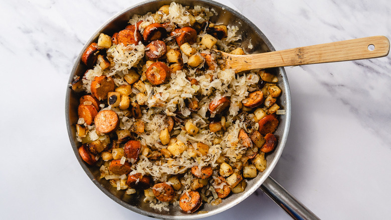 Smoked sausage and sauerkraut skillet with wooden spoon