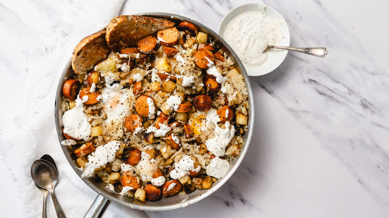 Smoked sausage and sauerkraut skillet with spoons and sauce on the side