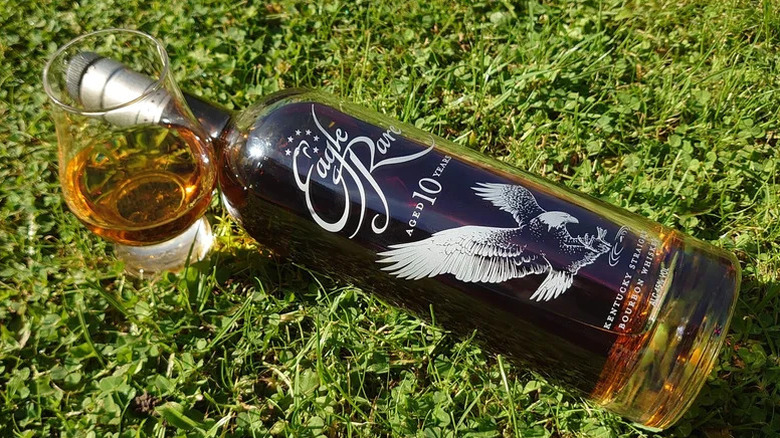 A bottle of Eagle Rare 10-year laid on the grass next to a filled glass