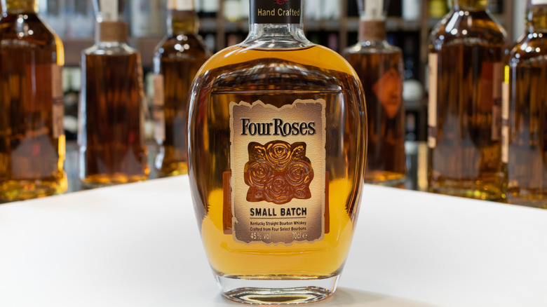 A bottle of Four Roses Small Batch on a white table with blurred bottles shown in the background