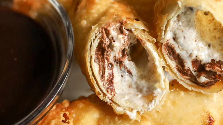 broken-open dessert egg roll with bowl of chocolate sauce