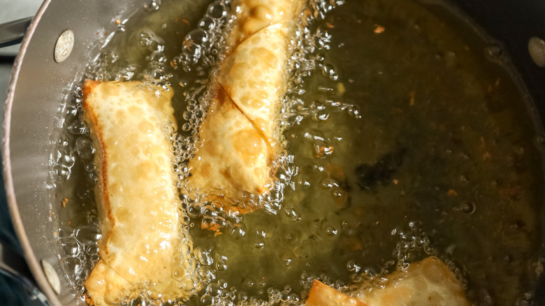 cooked egg rolls in pot of oil