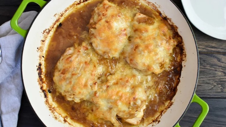 A French Onion chicken bake in a green pot on a wooden table