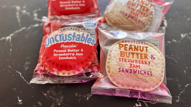 Uncrustables in wrappers next to Trader Joe's crustless PB&J sandwiches in wrappers