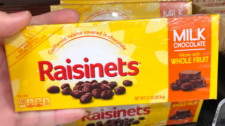 A person holding a box of Raisinets