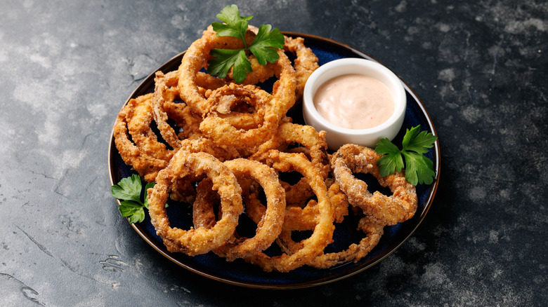 onoin rings on a plate with sauce