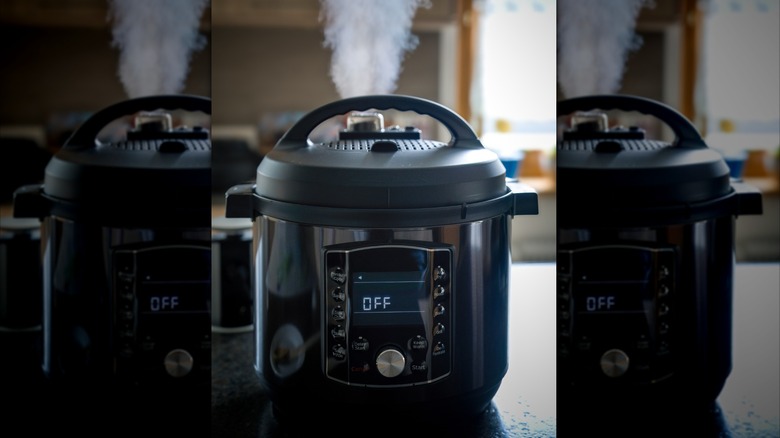 Steam billowing up from the lid of a pressure cooker