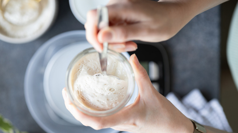 Person spooning sourdough starter after a jar