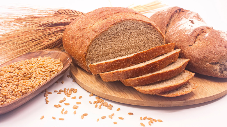 Whole grain bread loaf surrounded by wheat