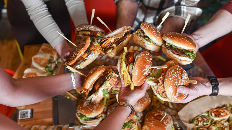 People holding hamburgers in restaurant.