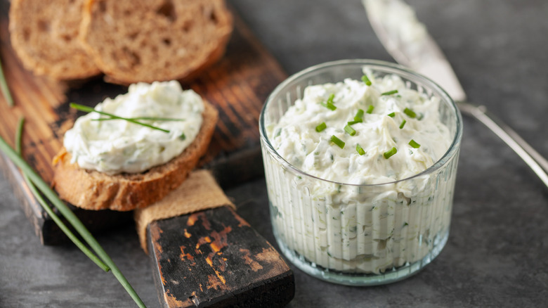 Bowl of Benedictine spread next to slices of baguette on wooden cutting board