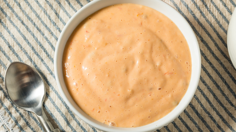 Bowl of creamy comeback sauce in white bowl on striped linen