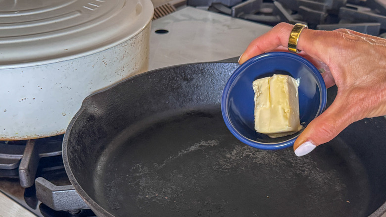 hand adding butter to pan