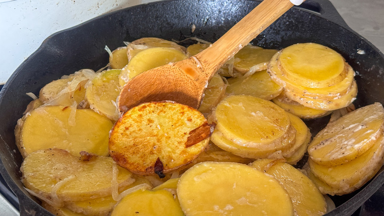 stirring potato slices in skillet