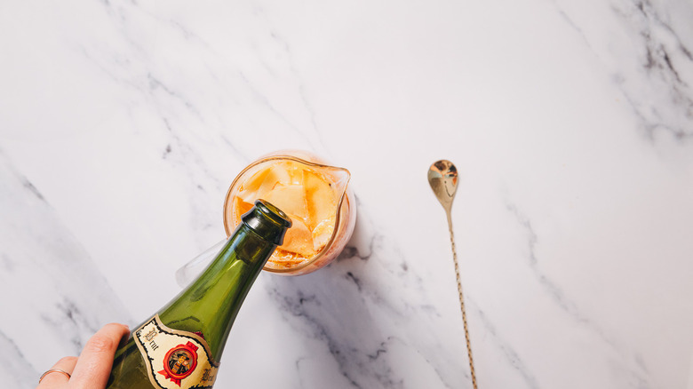 Adding sparkling hard cider to pitcher with sangria base