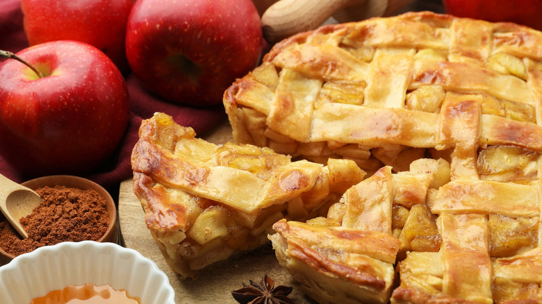 apple pie with bowl of cinnamon powder and apples