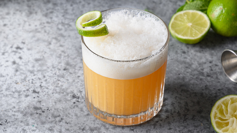 a whiskey sour with lime garnish