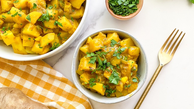 bowl of aloo curry with gold fork