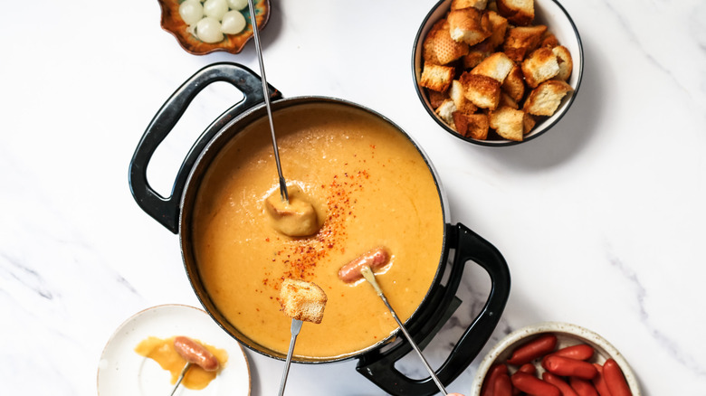 People dipping toasted bread and sausages into fondue