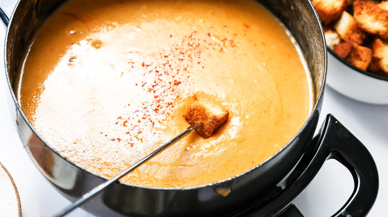 Dipping toasted bread into fondue