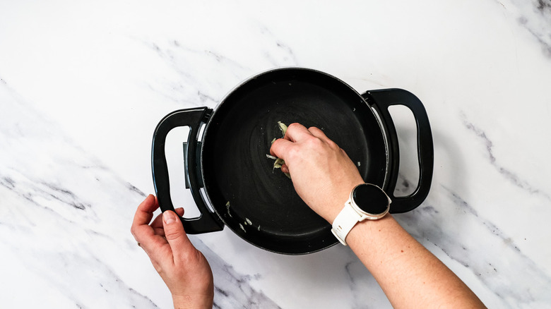 Rubbing the inside of a fondue pot with garlic