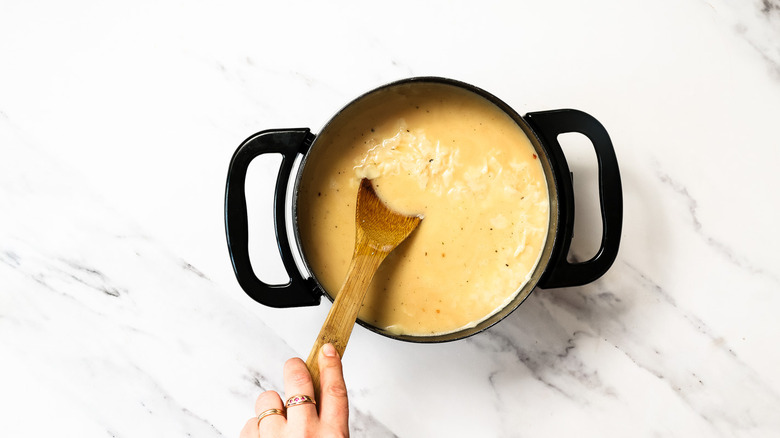 mixing in cheeses and spices into fondue pot