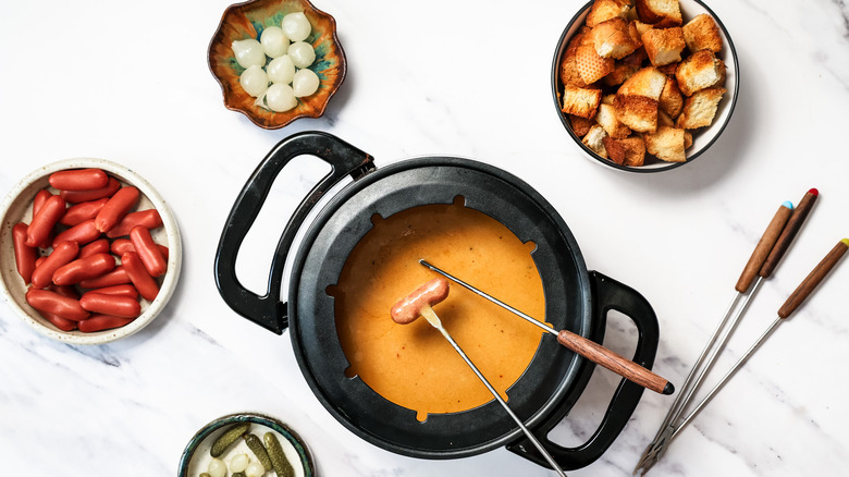 People dipping toasted bread and sausages into fondue