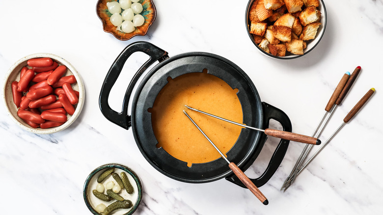 People dipping toasted bread and sausages into fondue