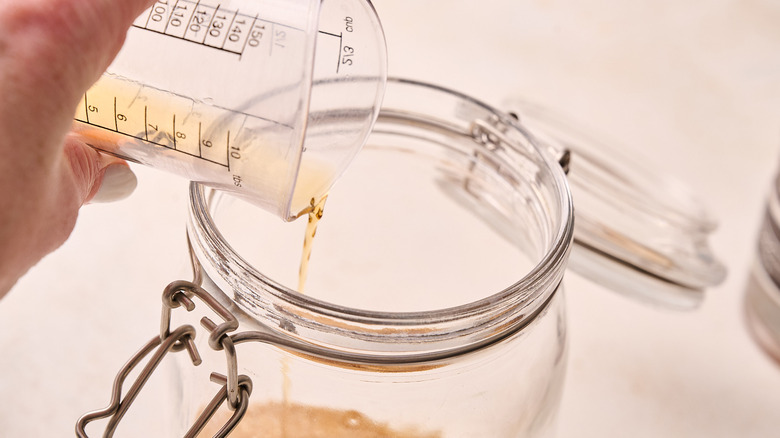 adding bourbon to a jar of sugar