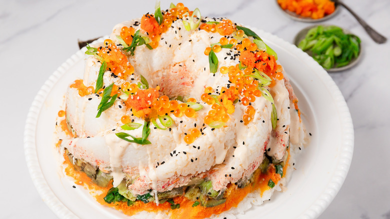 A fully assembled sushi bundt bake with toppings around.