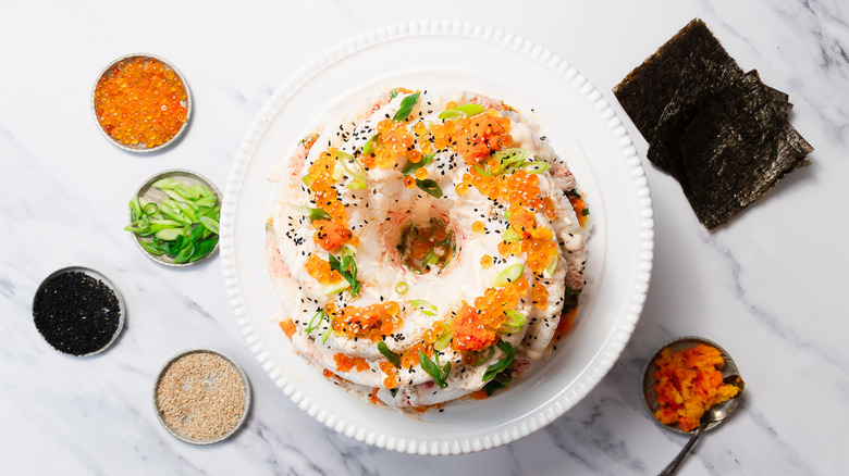 sushi bundt cake on cake stand with nori and toppings