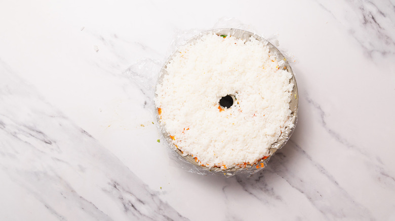 layered rice on top of sushi bake in plastic wrapped bundt cake
