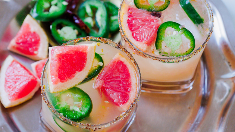 Two glasses of spicy mezcal margarita with garnishes
