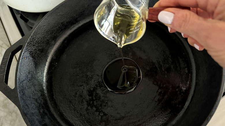 hand putting oil in pan