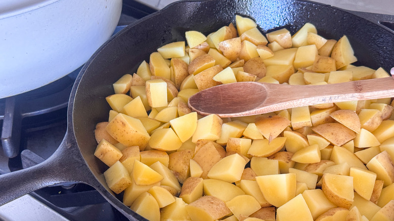 wooden spoon in skillet with potatoes