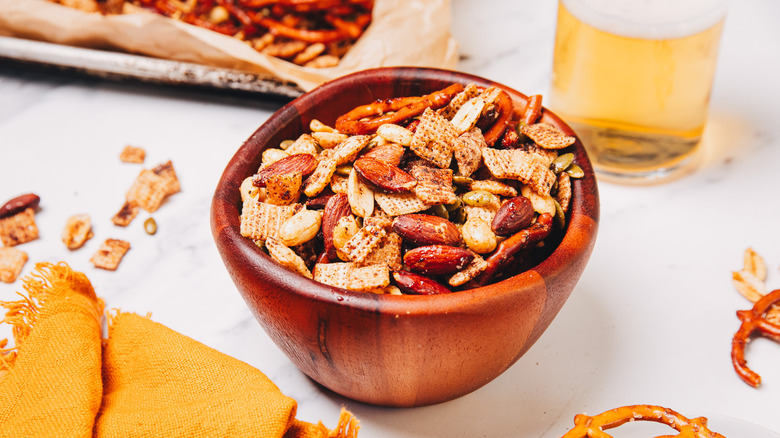 Bowl of spicy savory snack mix near beer.