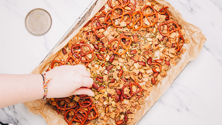 Adding salt into savory snack mix.