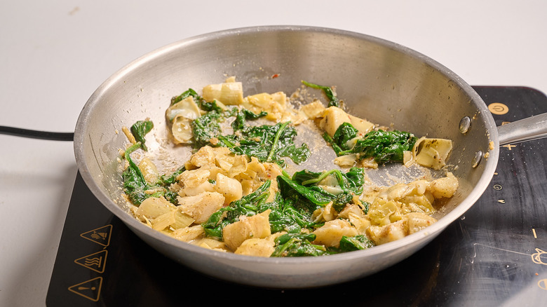 cooking artichokes in a skillet with seasoning