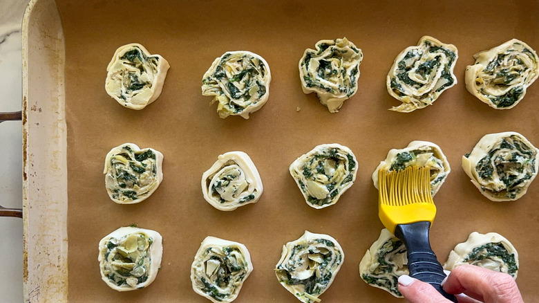 hand brushing pastry pinwheel with egg wash